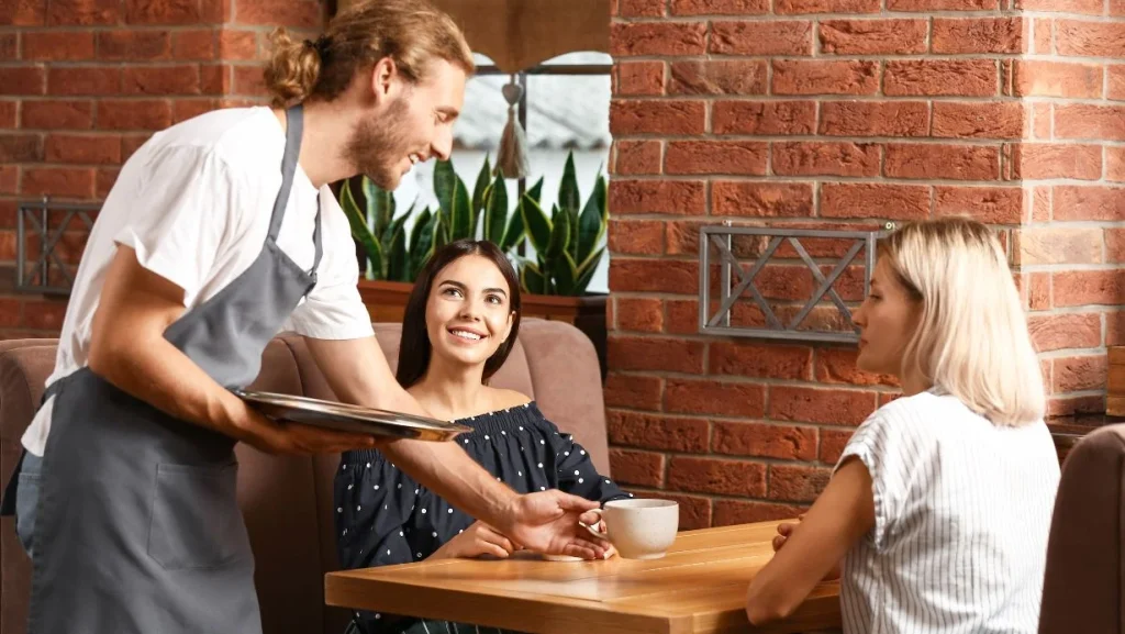 Waiter Serving Clients In Restaurant 1024x577