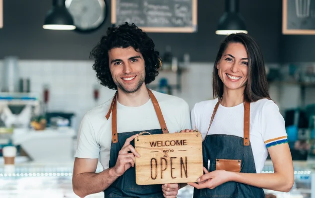 Business Owners Holding Welcome Were Open Signage